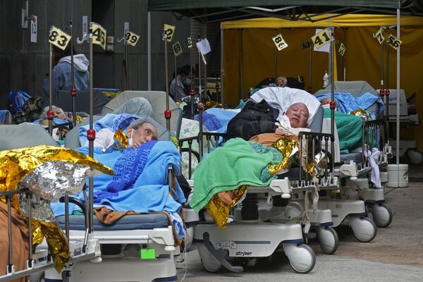 المرضى يرقدون على أسرة المستشفى أثناء انتظارهم في منطقة احتجاز مؤقتة خارج مركز كاريتاس الطبي في هونغ كونغ 16 فبراير 2022 - سبوتنيك عربي
