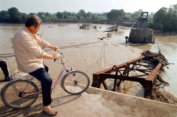راكب دراجة يلقي نظرة على الجسر المدمر في فارفارين، بالقرب من كروسيفاتش وسط صربيا، والذي سقط خلال الضربات الجوية لحلف شمال الأطلسي على يوغوسلافيا، 1 أغسطس/ آب 1999 - سبوتنيك عربي