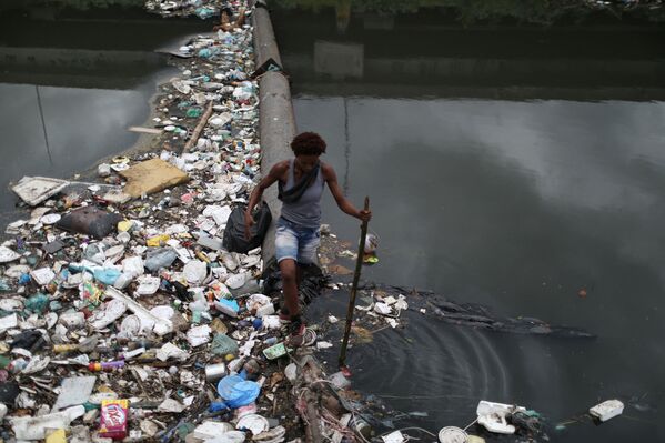 كلوديا ستيلا ألفيس دوس ريس، امرأة 24 عامًا، تسير بين القمامة التي تم التخلص منها على نهر أرويو فوندو في يوم المياه العالمي في ريو دي جانيرو، البرازيل، 22 مارس 2022. - سبوتنيك عربي