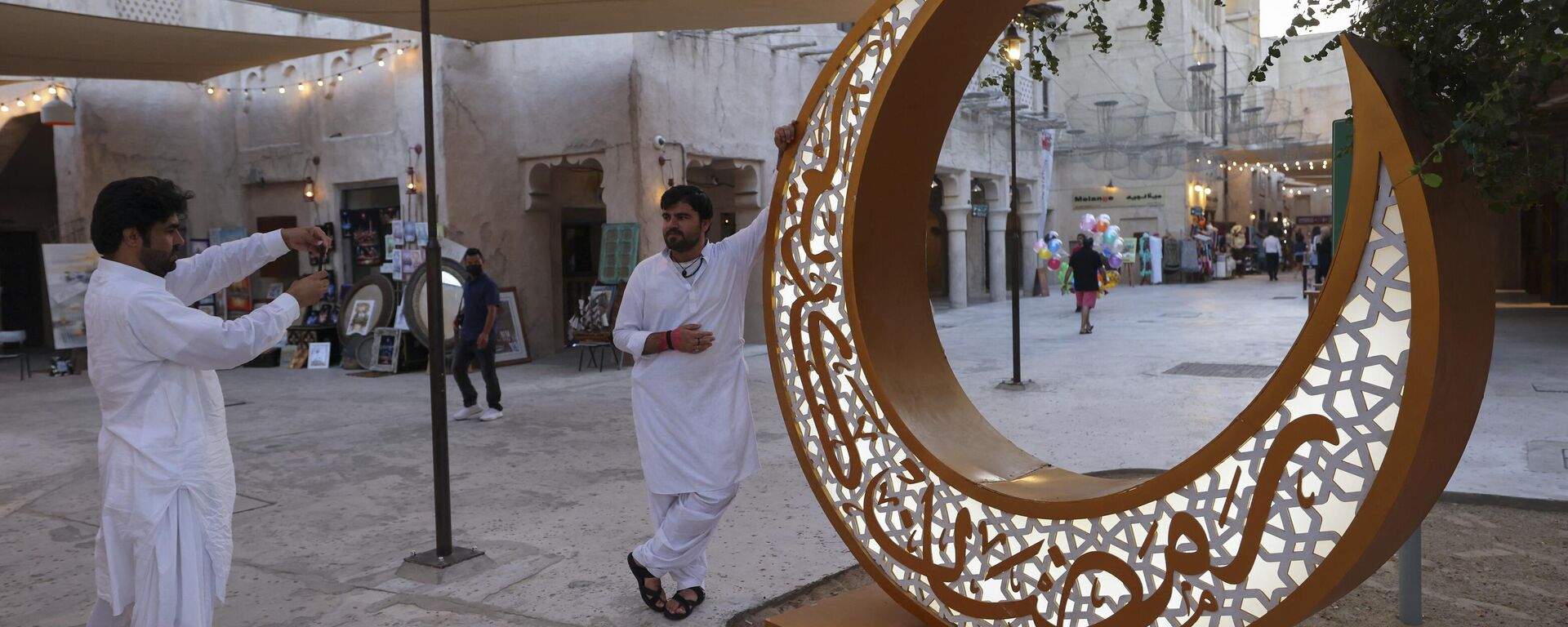 أشخاص يقفون لالتقاط صور بجوار زينة رمضان على شكل هلال الأول من رمضان إيذانا ببداية شهر رمضان المبارك في منطقة السيف بإمارة دبي، 1 أبريل 2022. - سبوتنيك عربي, 1920, 06.03.2023