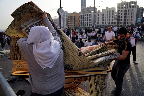 رجال يجمعون السجاد بعد أن أدى المصلون صلاة عيد الفطر خارج مسجد محمد الأمين في وسط بيروت، لبنان 2 مايو 2022. - سبوتنيك عربي