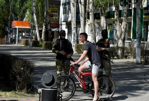 راكب دراجة أمام جنود روس يقومون بدورية في الشارع في مدينة سكادوفسك، منطقة خيرسون، وسط العملية العسكرية الروسية المستمرة في أوكرانيا، في 20 مايو 2022  - سبوتنيك عربي