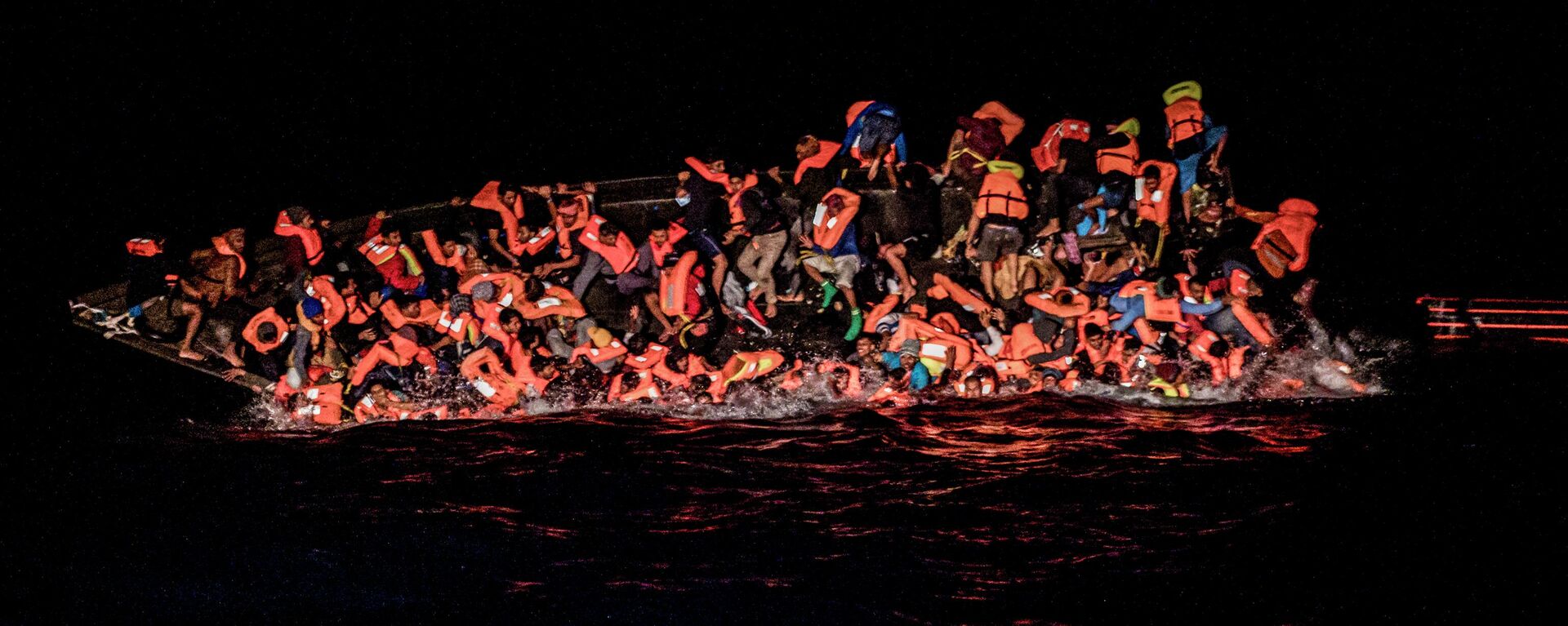 صورة تظهر لحظة سقوط العشرات من المهاجرين في المياه بينما يحولون التشبث بجانب قارب مقلوب قبالة مياه تونس في وقت مبكر 25 مايو 2022 - سبوتنيك عربي, 1920, 08.07.2023