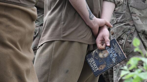 جنودي أوكراني أسير يحمل كتابا  في أحد السجون بجمهورية دونيتسك الشعبية - سبوتنيك عربي