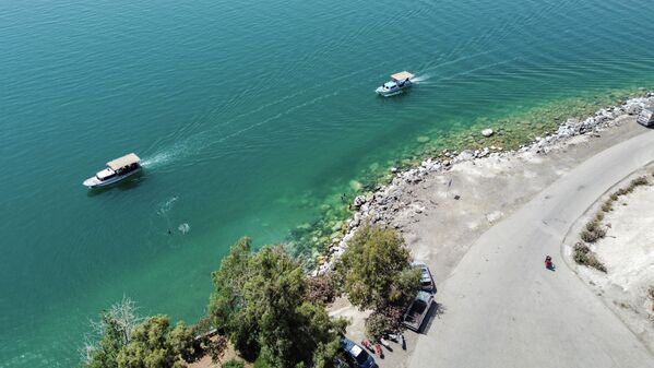 منظر جوي للقوارب المبحرة أمام أشخاص يسبحون قبالة ساحل قلعة جعبر في بحيرة الأسد بمحافظة الرقة السورية، 3  يونيو 2022 - سبوتنيك عربي