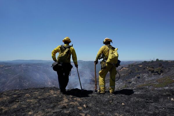 رجالا الإطفاء كيفن شلانج، إلى اليسار، وأنطونيو مورينو، إلى اليمين، ينظران إلى المناظر الطبيعية المحترقة التي سببها حريق إلكترا في جولد كنتري بكاليفورنيا بالقرب من جاكسون، كاليفورنيا، 7 يوليو 2022. حريق الغابات الذي اندلع يوم 4 يوليو 2022 ، 6.4 ميل مربع، (16.6 كيلومترًا مربعًا) تم احتواؤها الآن بنسبة 40% دون حرق أي مبانٍ. - سبوتنيك عربي