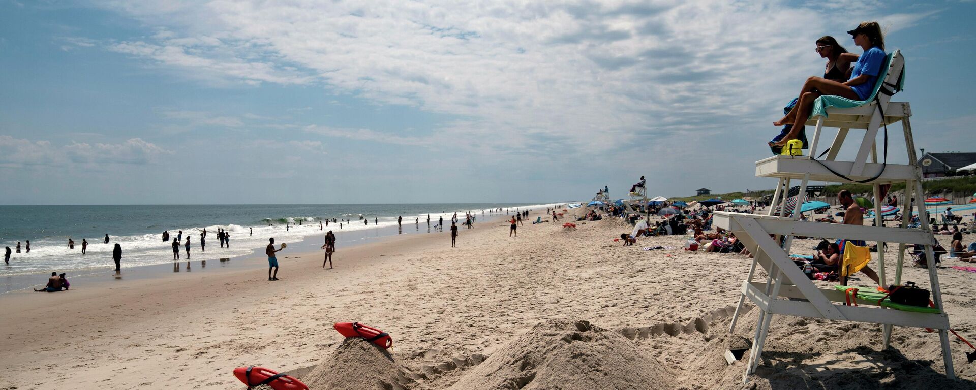 رواد الشاطئ يستمتعون بركوب الأمواج بينما ينظر رجال الإنقاذ إلى حديقة سميث بوينت كاونتي بارك، وهو شاطئ لونغ آيلاند حيث قام سمك القرش بتدوير منقذ قبل 10 أيام، في شيرلي، نيويورك 15 يوليو 2022  - سبوتنيك عربي, 1920, 09.05.2024