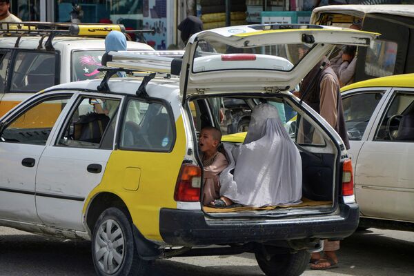 هذه الصورة التي التقطت في 19 يوليو 2022، تظهر امرأة وطفل ينتظران في مؤخرة سيارة أجرة للتنقل في قندهار.  بعد مرور عام على عودة طالبان إلى السلطة في أفغانستان، بدأت بعض الانقسامات في صفوفهم تتفتح حول السؤال الحاسم حول مدى الإصلاح الذي يمكن أن يتحمله قادتهم. توعد الإسلاميون، الذين اشتهروا خلال فترة حكمهم الأولى بسبب حملات القمع الوحشية للحقوق والحريات، بالحكم بشكل مختلف هذه المرة.  - سبوتنيك عربي