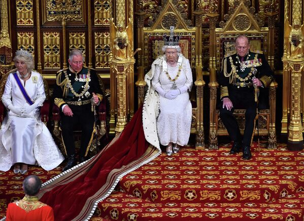 ملكة بريطانيا إليزابيث الثانية، الثانية من اليمين، جالسة على العرش في مجلس اللوردات بجوار زوجها الأمير فيليب ، دوق إدنبرة، على اليمين، ابنها، الأمير تشارلز، أمير ويلز، الثاني من اليسار وزوجته كاميلا، دوقة كورنوال، يستعد لإلقاء خطاب الملكة خلال افتتاح الدولة للبرلمان في قصر وستمنستر في لندن في 27 مايو 2015. يمثل الافتتاح الرسمي للبرلمان بداية رسمية للسنة البرلمانية ويحدد خطاب الملكة جدول أعمال الحكومة الجلسة القادمة. - سبوتنيك عربي