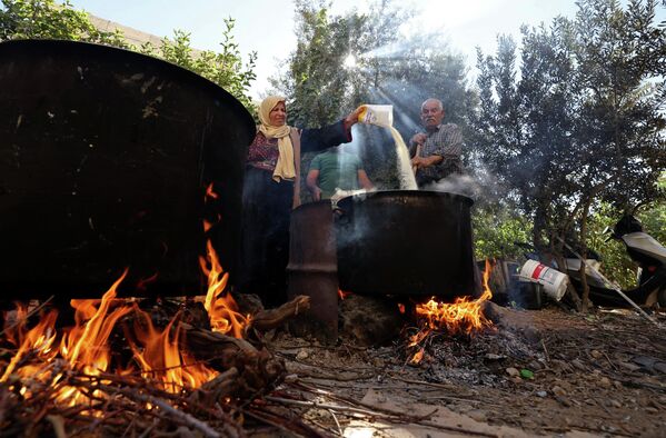 الفلسطيني عبد اللطيف كراجه وزوجته نبيهة يحضران حلويات الملبن التقليدية المصنوعة من عصير العنب، في قرية حلحول بالقرب من مدينة الخليل بالضفة الغربية المحتلة، 12 سبتمبر 2022. - سبوتنيك عربي