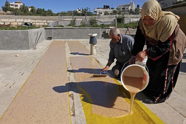 الفلسطيني عبد اللطيف كراجه وزوجته نبيهة يحضران حلويات الملبن التقليدية المصنوعة من عصير العنب، في قرية حلحول بالقرب من مدينة الخليل بالضفة الغربية المحتلة، 12 سبتمبر 2022. - سبوتنيك عربي