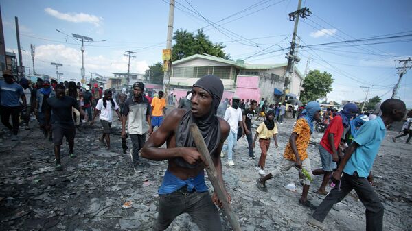 متظاهر يحمل قطعة من الخشب تحاكي سلاحًا خلال مظاهرة تطالب باستقالة رئيس الوزراء أرييل هنري، في منطقة بيتيون فيل في بورت أو برنس، هايتي، يوم 3 أكتوبر 2022. - سبوتنيك عربي