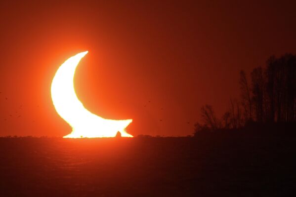 كسوف جزئي للشمس يظهر عند غروب الشمس بالقرب من نوفوسيبيرسك، روسيا 25 أكتوبر 2022 - سبوتنيك عربي