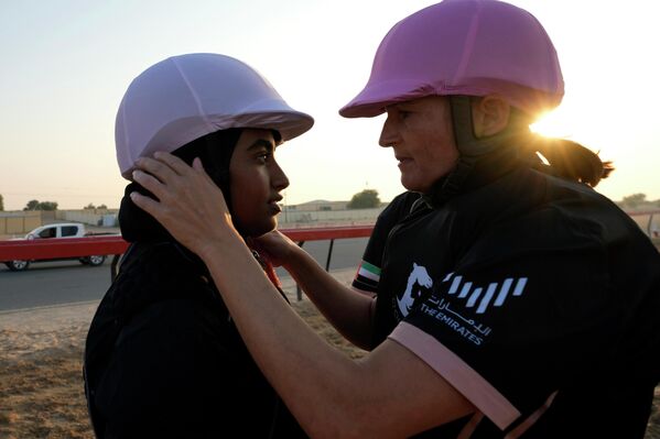 راكبة الجمال النيوزيلندية، جودي ريتشاردز، إلى اليمين، ترافق خديجة من الإمارات العربية المتحدة قبل السباق الأول للموسم الذي ينظمه مركز ركوب الجمال في الصحراء العربية في مضمار المرموم في ضاحية دبي، الإمارات العربية المتحدة، 29 أكتوبر 2022. - سبوتنيك عربي