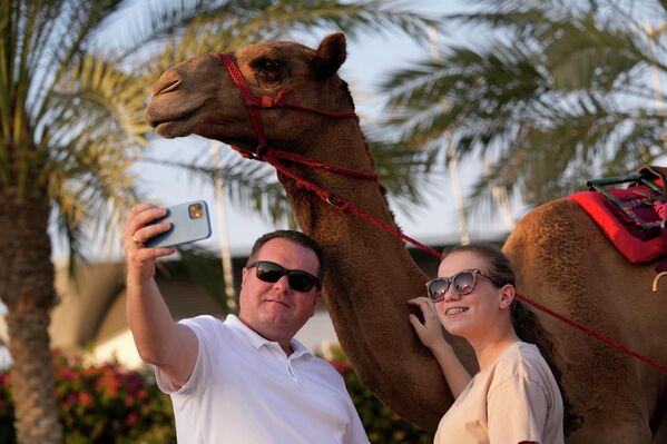 المشجعون يلتقطون صورة سيلفي مع جمل قبل السباق الأول للسيدات في الموسم الذي نظمه مركز الصحراء العربية لركوب الجمال في مضمار المرموم للسباق بضاحية دبي، الإمارات العربية المتحدة، 29 أكتوبر 2022. - سبوتنيك عربي