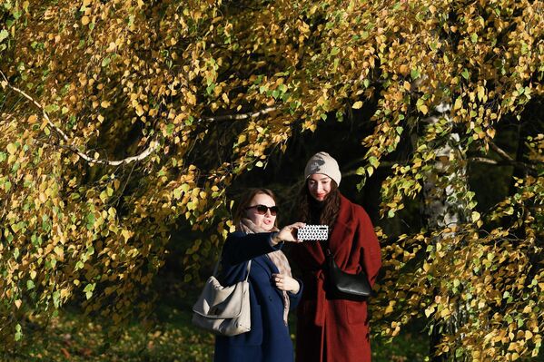 النساء يلتقطن صورة على خلفية في محمية متحف كومسومولسكويه في موسكو، روسيا 16 أكتوبر 2022 - سبوتنيك عربي