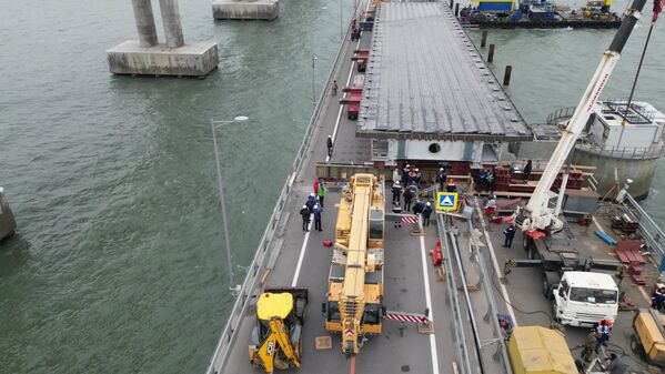 عمال البناء يقومون باستكمال المرحلة الأولى من ترميم الأجزاء المتضررة من مسار الطريق على جسر القرم الروسي. - سبوتنيك عربي