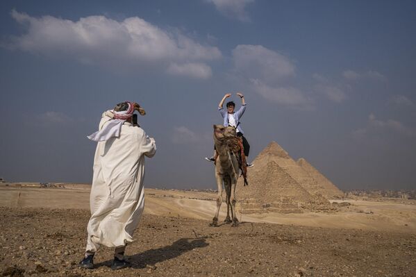 سائح يركب جمل يقف لالتقاط صورة من مرتفع يطل على مقبرة أهرامات الجيزة في ضواحي القاهرة، مصر 12 نوفمبر 2022. - سبوتنيك عربي