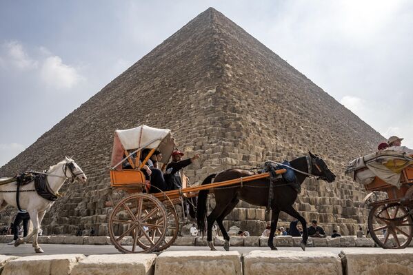 يركب الزوار والسياح عربات تجرها الخيول خارج الهرم الأكبر للملك المصري القديم خوفو (الذي بني حوالي 2570 قبل الميلاد) في مقبرة الجيزة على مشارف القاهرة، مصر 12 نوفمبر 2022. - سبوتنيك عربي