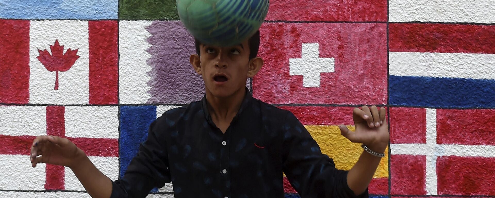 في هذه الصورة التي تم التقاطها في 7 نوفمبر 2022، يلعب صبي كرة القدم أمام جدارية قبل انطلاق بطولة كأس العالم لكرة القدم قطر 2022، على طول شارع في كراتشي. - سبوتنيك عربي, 1920, 29.11.2022