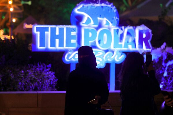 سعوديون يقفون على خلفية حانة "بولار آيس بار"، المصنوعة من الجليد،" التي افتتحت حديثًا في الرياض، حيث الإيقاعات الموسيقية ويتم تقديم مشروبات غير كحولية، ضمن "موسم الرياض"، إحدى مبادرات الهيئة السعودية للترفيه، 28 نوفمبر 2022 - سبوتنيك عربي