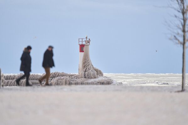 الناس يسيرون على طول ممر خشبي مغطى بالجليد في بورت ستانلي، أونتاريو، كندا، في 27 ديسمبر 2022. - سبوتنيك عربي