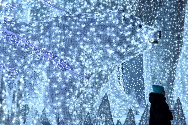 امرأة تسير أمام زينة عيد الميلاد ورأس السنة الجديدة في موسكو في 7 يناير 2023، حيث انخفضت درجة حرارة الهواء في العاصمة الروسية إلى 20 درجة مئوية تحت الصفر. - سبوتنيك عربي