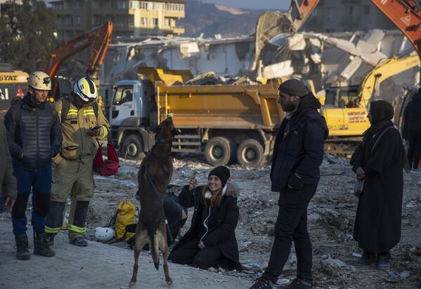 امرأة تلعب مع كلب بوليسي بينما يواصل عمال الإنقاذ البحث عن ضحايا الزلزال الذي وقع في أنطاكيا، تركيا، 11 فبراير 2023 - سبوتنيك عربي