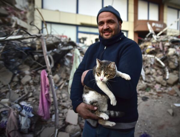 رجل يحمل قطته التي تم إنقاذها من مبنى منهار في كهرمان مرعش التركية 11 فبراير 2023 - سبوتنيك عربي