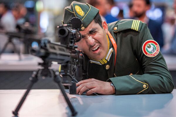 أحد زوار معرض آيدكس 2023 يتفحص بندقية هجومية خلال معرض الدفاع الدولي في مركز أبوظبي الدولي للمعارض، الإمارات العربية المتحدة في 20 فبراير 2023. - سبوتنيك عربي
