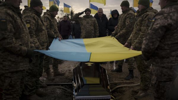 جنود أوكرانيون يرفعون علمهم الوطني فوق نعش رفيقهم، خلال جنازته في بوتشا، ضواحي كييف، أوكرانيا ، 23 ديسمبر 2022. - سبوتنيك عربي