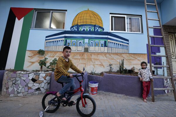 صبي يركب دراجة أمام منزله، المرسوم عليه مسجد قبة الصخرة، رسمت بألوان زاهية كجزء من مبادرة لفنان فلسطيني، في حي الزيتون بمدينة غزة، قطاع غزة، فلسطين 12 مارس  2023. - سبوتنيك عربي
