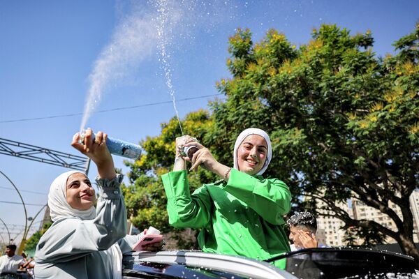 طلاب فلسطينيون يخرجون من نوافذ وكوة سيارة لرش الرغوة أثناء احتفالهم بتخرجهم بعد أن أعلنت وزارة التربية الفلسطينية نتائج امتحانات شهادة الثانوية العامة في مدينة الخليل في الضفة الغربية المحتلة، في 20 يوليو 2023. - سبوتنيك عربي