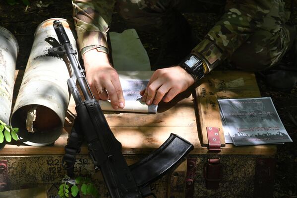 جندي روسي يقوم بجمع منشورات لإرسالها لقوات الجيش الأوكراني في إتجاه محور سفاتوف، جمهورية لوغانسك الشعبية. - سبوتنيك عربي