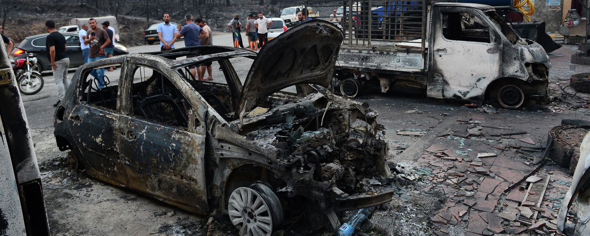 أشخاص يتفقدون المركبات المحترقة بعد اندلاع حرائق الغابات في البويرة، على بعد 100 كلم من الجزائر العاصمة، الجزائر، يوم 24 يوليو 2023. - سبوتنيك عربي, 1920, 24.07.2025
