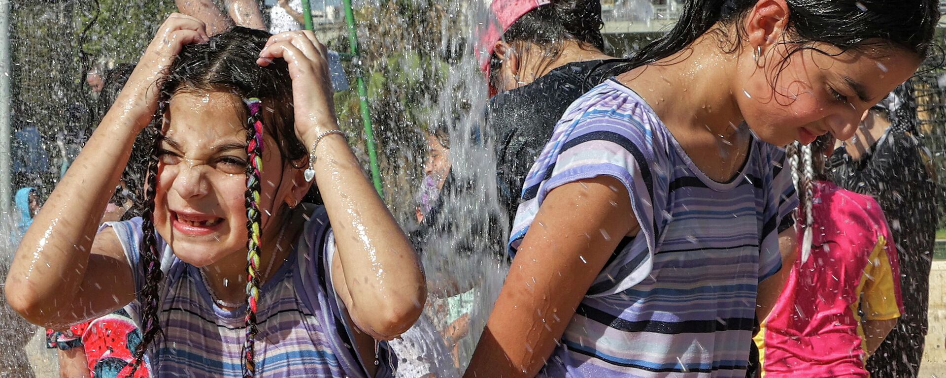 أطفال يتفاعلون أثناء استحمامهم برذاذ نافورة لكي يبردوا أثناء موجة حارة - سبوتنيك عربي, 1920, 07.08.2023