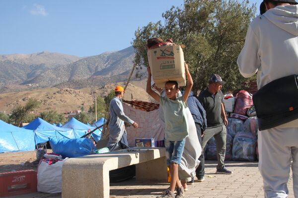 طفل مغربي في العاشرة من عمره يحمل المساعدات على رأسه لنقلها إلى المناطق المنكوبة - سبوتنيك عربي