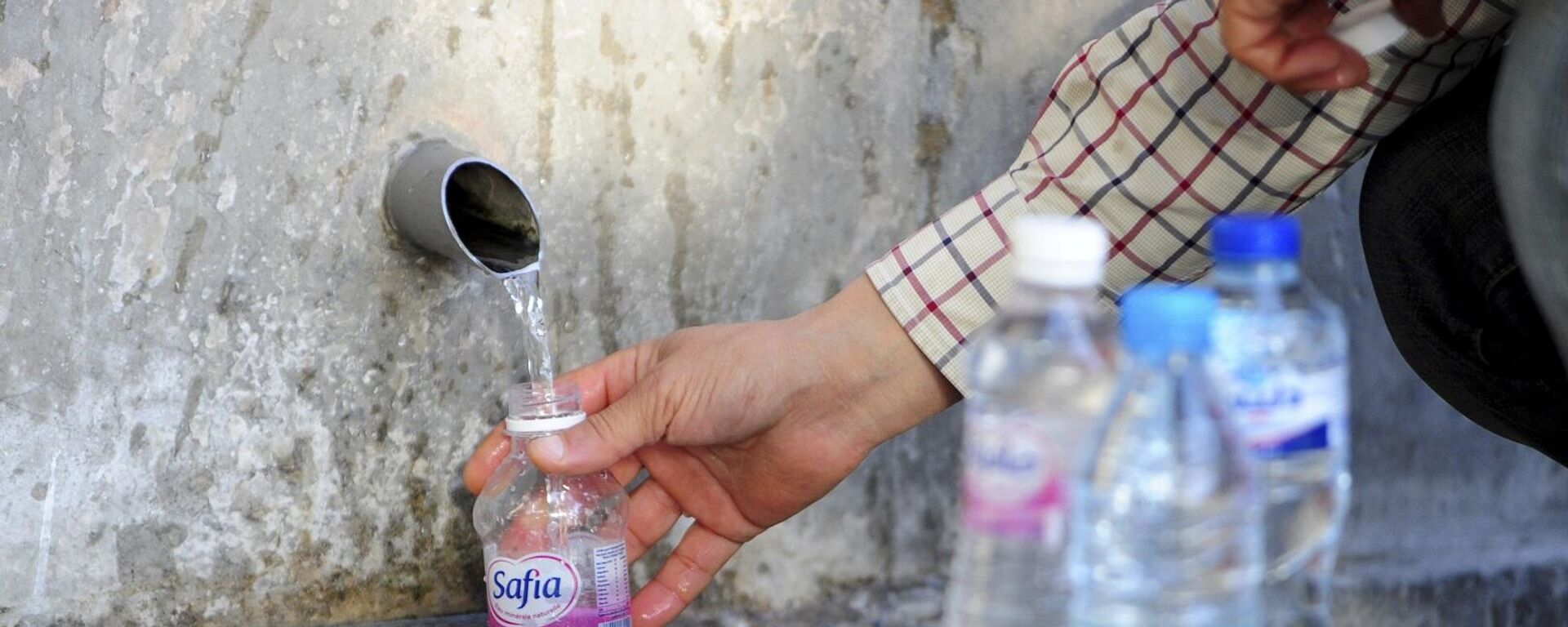 رجل يملأ زجاجة بمياه صالحة للشرب من مصدر في سيدي بوسعيد، شمال تونس العاصمة، وسط خوض البلاد معركة ضد الجفاف الشديد المتزايد، 12 نيسان/ أبريل 2023 - سبوتنيك عربي, 1920, 10.10.2023