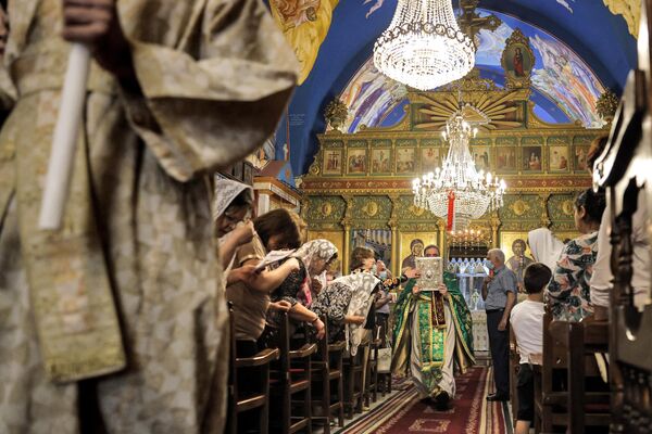 كاهن أرثوذكسي يوناني يسير أمام المصلين المسيحيين الفلسطينيين خلال قداس الأحد في كنيسة القديس برفيريوس في مدينة غزة ، 30 مايو 2021. - سبوتنيك عربي