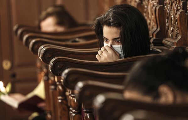 فلسطينية من الروم الأرثوذكس تعدل كمامة وجهها خلال احتفال قداس صباح عيد الفصح في كنيسة القديس برفيريوس في مدينة غزة ، في 2 مايو 2021. - سبوتنيك عربي