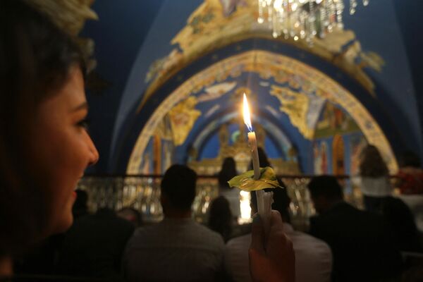 فلسطيني مسيحي أرثوذكسي يحمل شمعة مضاءة من &#x27;النار المقدسة&#x27; في كنيسة القديس برفيريوس في مدينة غزة في أوائل 8 أبريل  2018 خلال احتفالات عيد الفصح. - سبوتنيك عربي