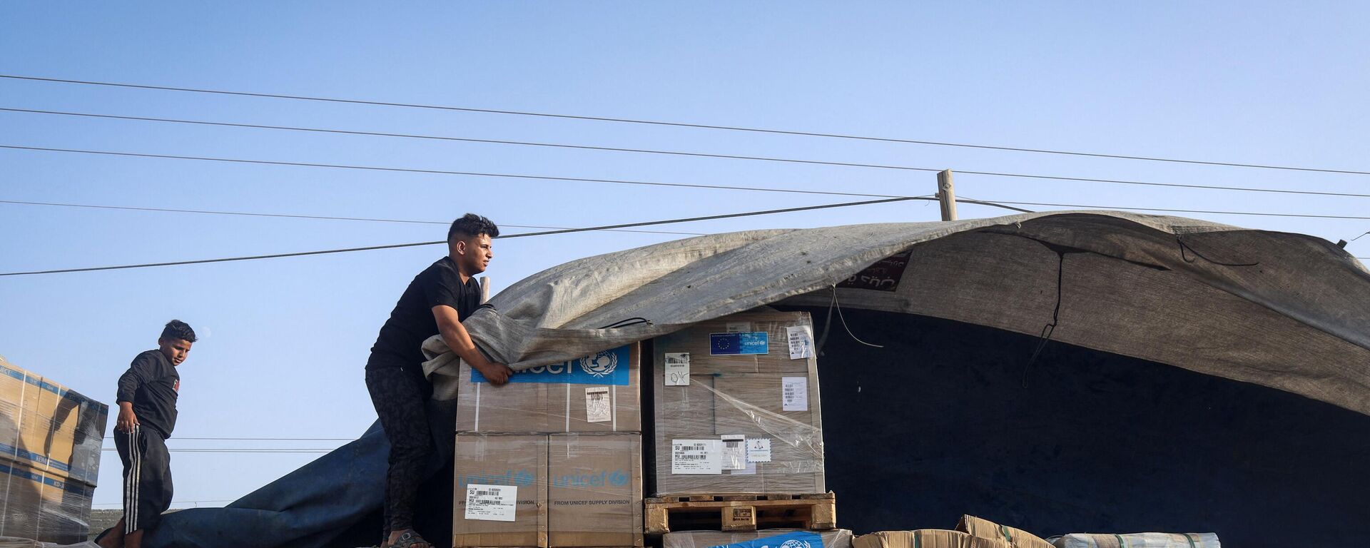 رجل يفرغ مساعدات إنسانية على قافلة شاحنات تدخل قطاع غزة من مصر عبر معبر رفح الحدودي في 21 أكتوبر 2023 - سبوتنيك عربي, 1920, 08.03.2024