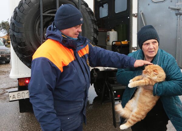 موظف في وزارة حالات الطوارئ الروسية وأحد سكان منزل تضرر نتيجة الكارثة الطبيعية في شبه جزيرة القرم الروسية.  - سبوتنيك عربي