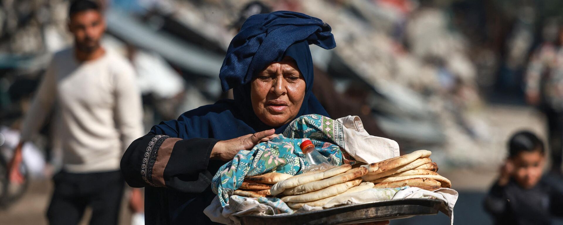 امرأة فلسطينية تحمل الخبز خارج مدرسة تابعة للأمم المتحدة في البريج بوسط قطاع غزة في 21 نوفمبر 2023، وسط المعارك المستمرة بين إسرائيل وحركة حماس الفلسطينية. - سبوتنيك عربي, 1920, 23.12.2023