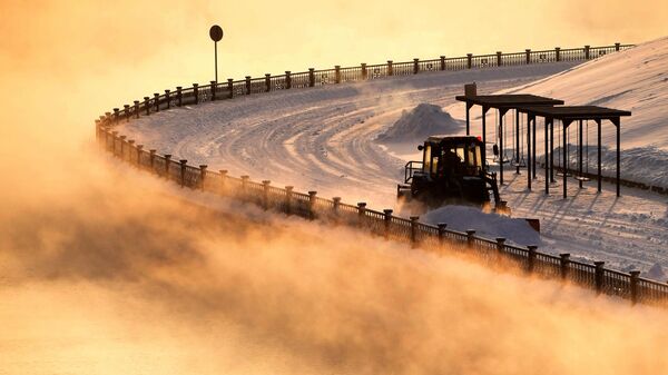 يقوم جرار بإزالة الثلوج عند درجة حرارة هواء تبلغ حوالي سالب 27 درجة مئوية على جسر ينيسي المركزي في كراسنويارسك. - سبوتنيك عربي