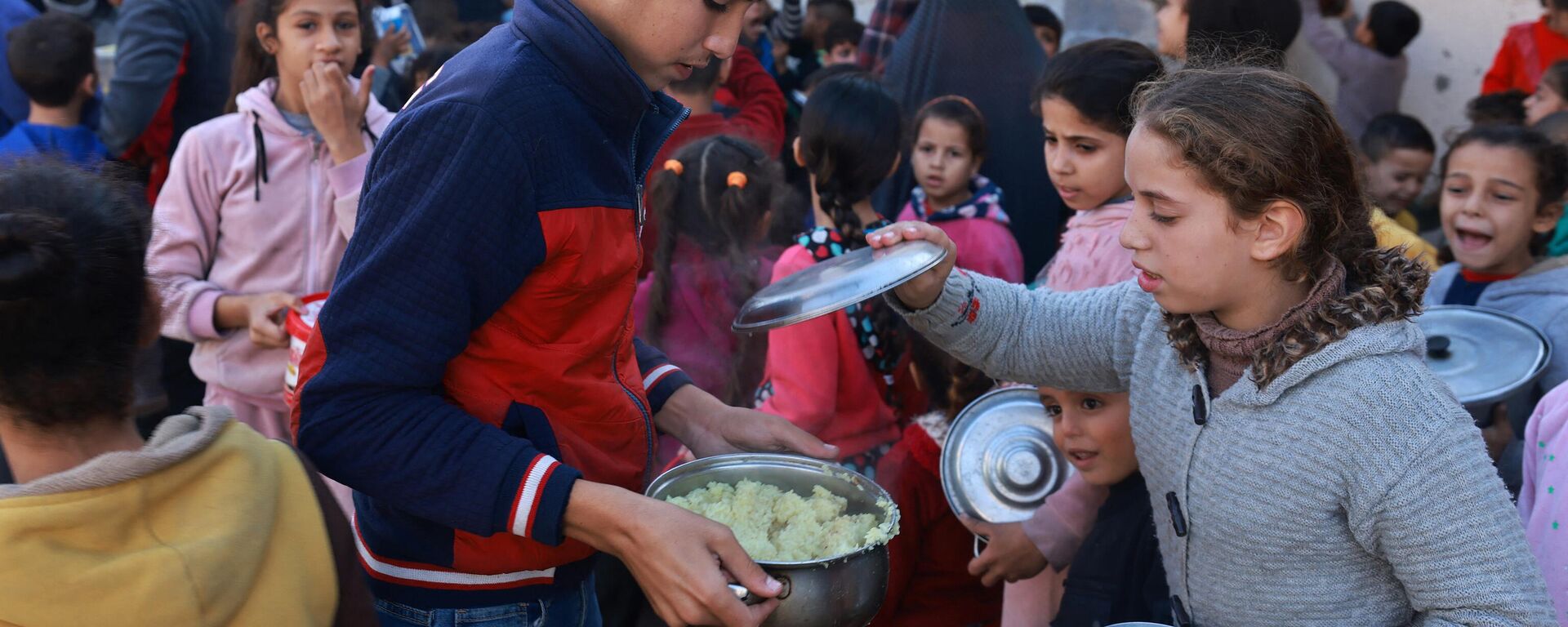 أطفال فلسطينيون يجمعون الطعام في نقطة تبرع  في مدينة رفح جنوب قطاع غزة، في 6 ديسمبر 2023، - سبوتنيك عربي, 1920, 01.01.2024