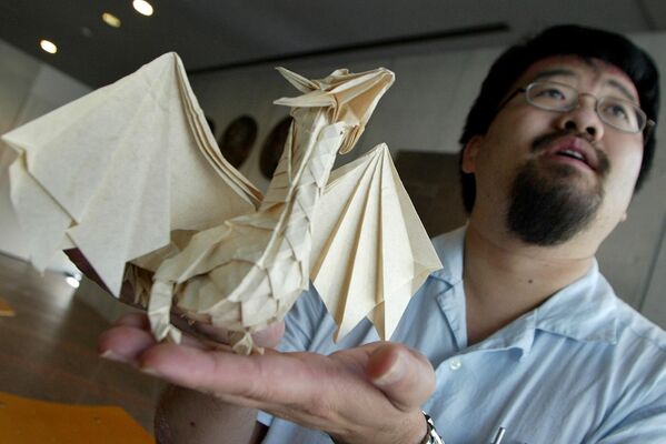 فنان الأوريغامي الكندي المحترف، جوزيف وو، يحمل عمله المفضل وهو تنين مصنوع من الورق. - سبوتنيك عربي