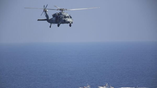 طائرة هليكوبتر أمريكية من طراز سي هوك-60 تحلق فوق زوارق دورية للحرس الثوري الإيراني في مضيق هرمز - سبوتنيك عربي