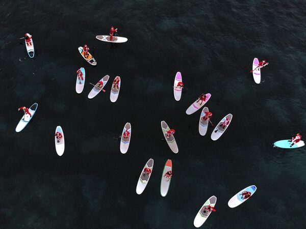 منظر جوي يظهر أشخاصا يرتدون ملابس سانتا كلوز وهم يركبون زوارق واقفة في البحر الأبيض المتوسط، في مدينة البترون الساحلية شمال لبنان في 21 ديسمبر 2023.  - سبوتنيك عربي