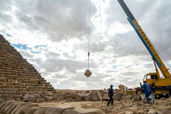 صورة لقيام العمال برفع الأحجار بواسطة رافعة أثناء العمل في المشروع لترميم قاعدة هرم &quot;منقرع&quot; - سبوتنيك عربي